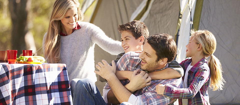 A happy family in a campsite in South Tyrol hugging each other in front of their tend