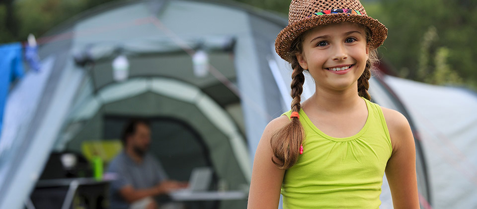 Bimba sorridente con cappello di paglia davanti alla sua tenda in Val Venosta