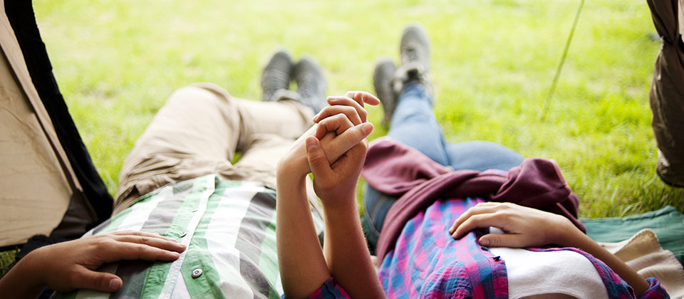 Ein händchenhaltendes Paar beim Entspannen im eigenen Zelt