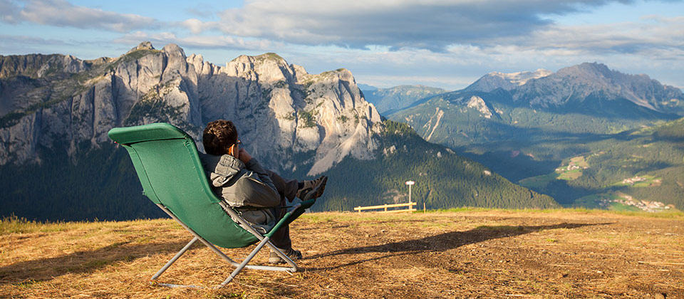 Uomo in sedia a sdraio si rilassa alla vista dall'alto delle Dolomiti