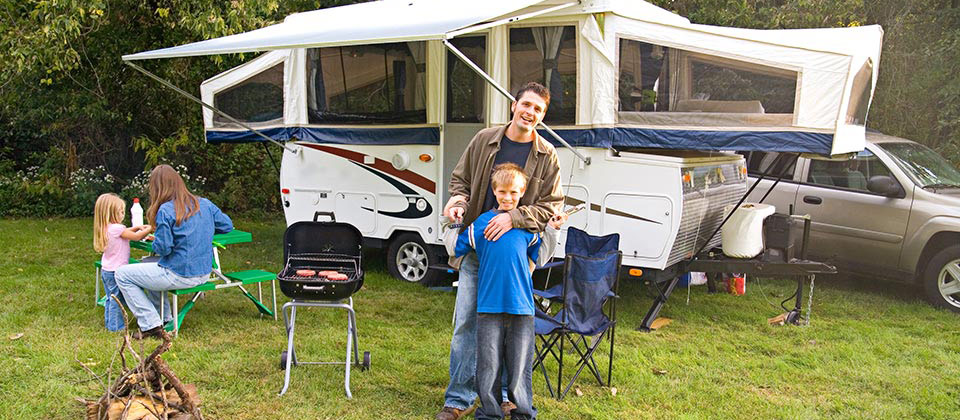 Famiglia al bordo di un bosco in Alto Adige intenta a grigliare davanti al loro camper