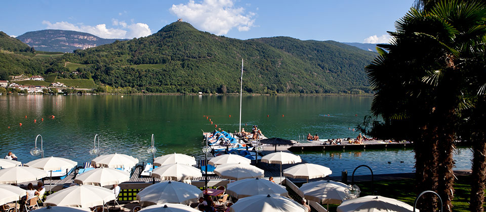 Fila di ombrelloni in riva al lago di Caldaro