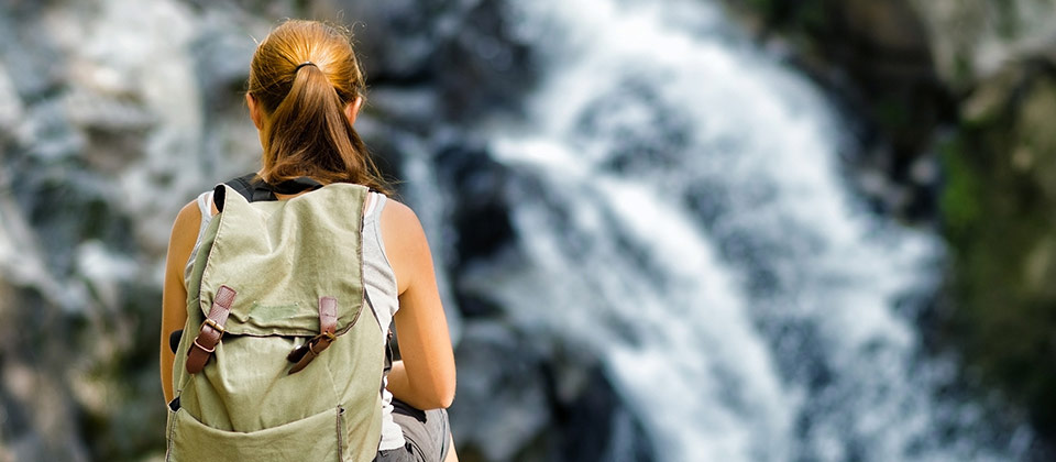 Donna seduta sui sassi di fronte a una cascata della Valle Isarco